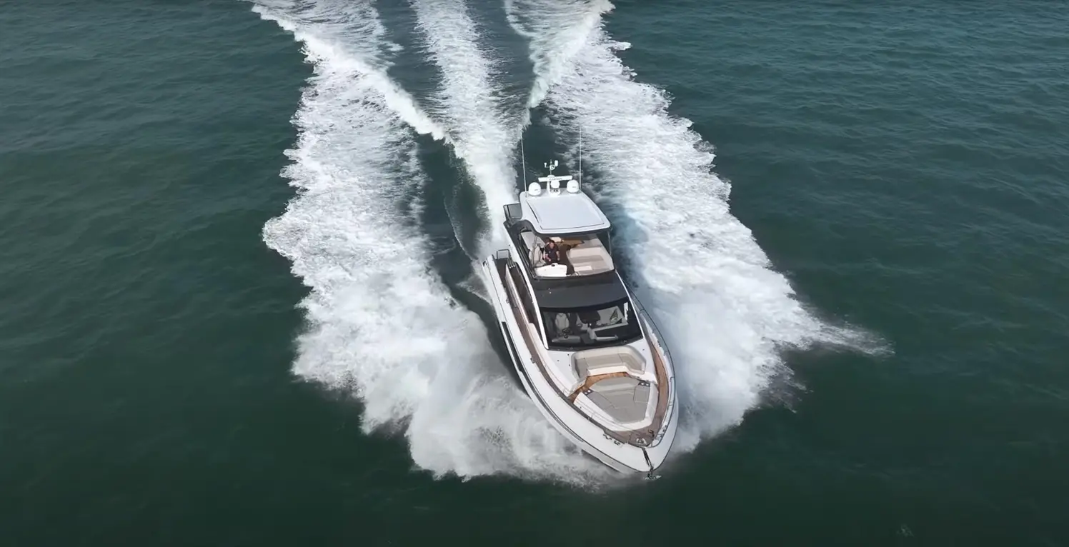 A luxury motorboat speeds through turquoise waters, leaving a wake as it navigates the ocean.